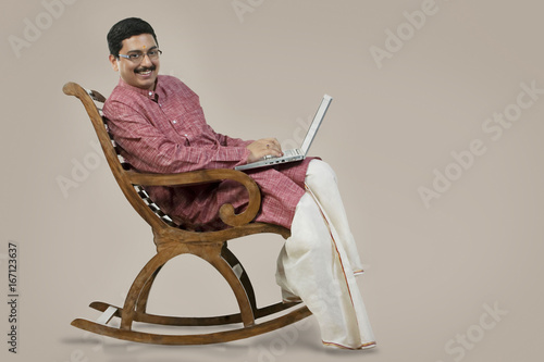 South Indian man on a chair with a laptop  photo