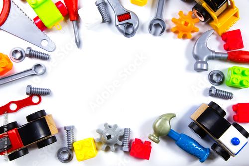 Kids toys frame with construction blocks, cubes, toy tools and cars on white background. Top view
