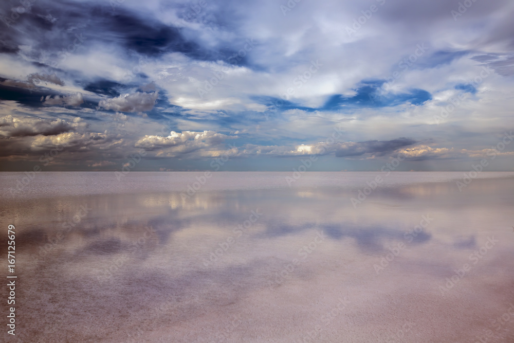 Clouds and reflections in a salt lake. Dramatic landscape.