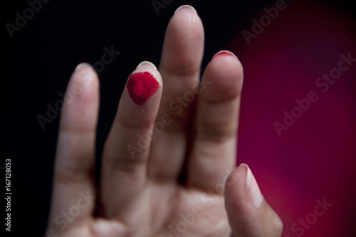 Close-up of human finger with red powder paint 