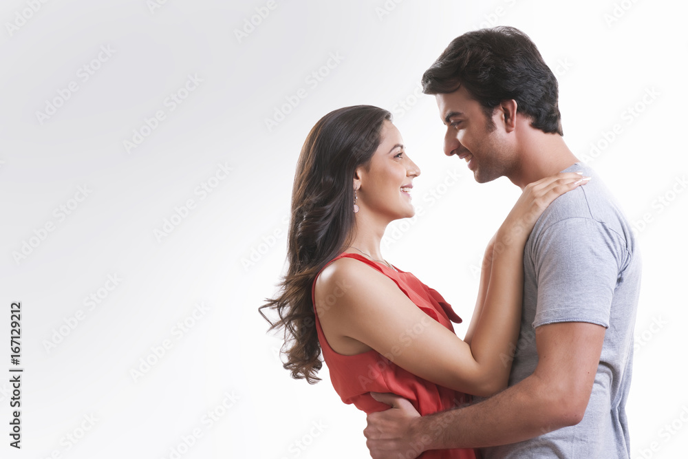 Profile shot of affectionate young couple looking at each other against white background Profile shot of affectionate young couple looking at each other against white background