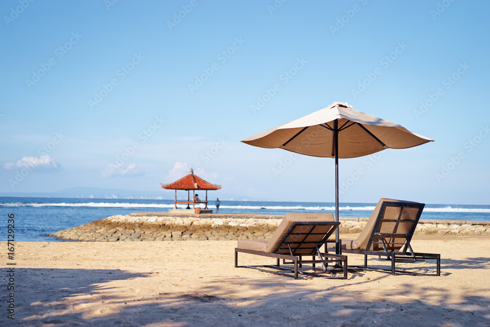 Vacation concept. Two sunloungers and umbrella on sand sea beach.