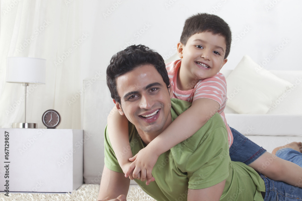 Portrait of happy son sitting on father at home Portrait of happy son sitting on father at home