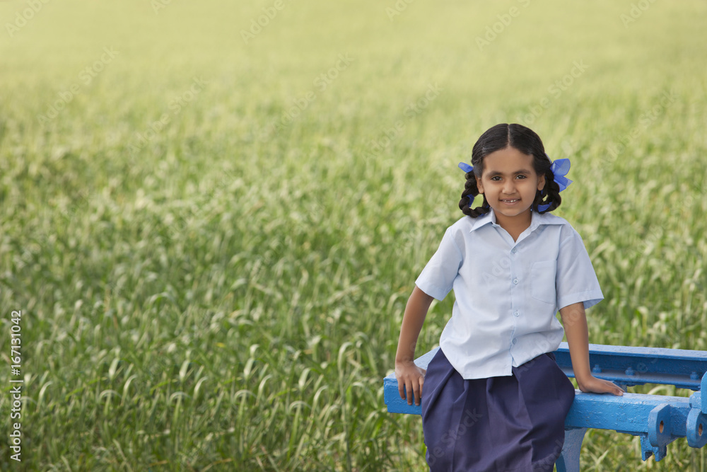 Portrait of a little rural school girl sitting in a field Portrait of a little rural school girl sitting in a field