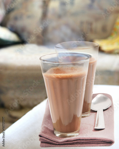 Glasses of morning chai with steel spoon kept on table napkin 