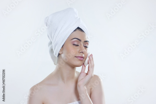 Young woman washing face with soap bar against white background