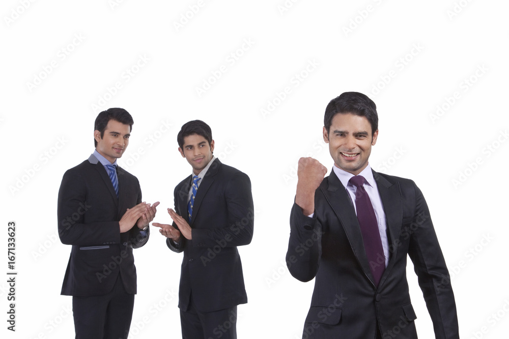 Colleagues clap as fellow businessman rejoices Colleagues clap as fellow businessman rejoices