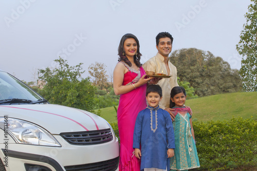 Portrait of family standing next to new car © IndiaPix
