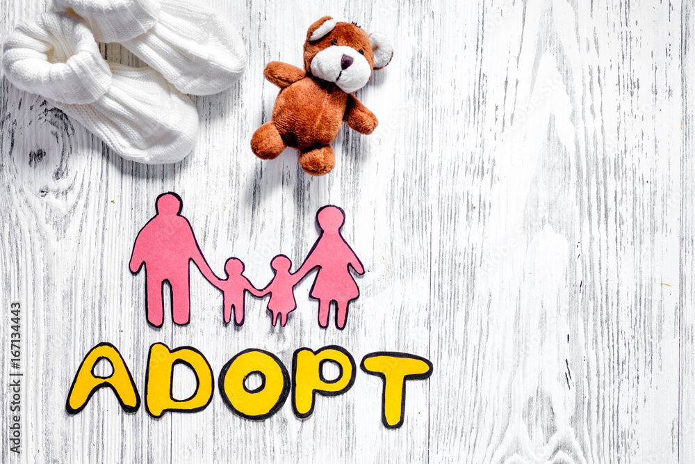 Adopt word, paper silhouette of family and toys on light wooden table background top view copyspace Adopt word, paper silhouette of family and toys on light wooden table background top view copyspace