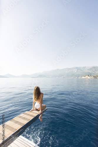 Young attractive woman sitting on  luxury yacht floating at sea