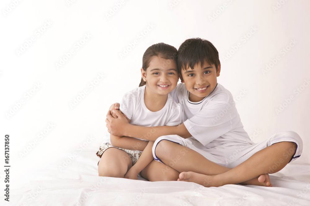 Portrait of happy brother embracing sister in bed Portrait of happy brother embracing sister in bed