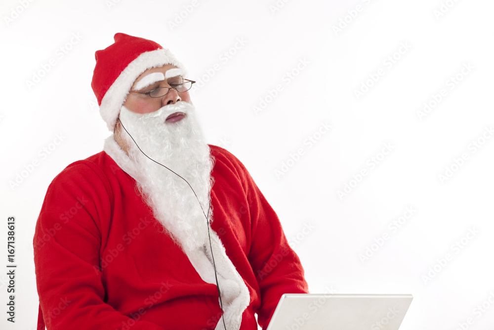 Naklejka premium Santa Claus listening to music with eyes closed while using laptop over white background 
