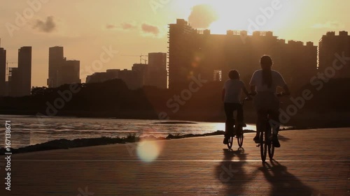 Silhouettes of people cycling at sunset; city of Shenzhen, Guangdong province, People's republic of China; 