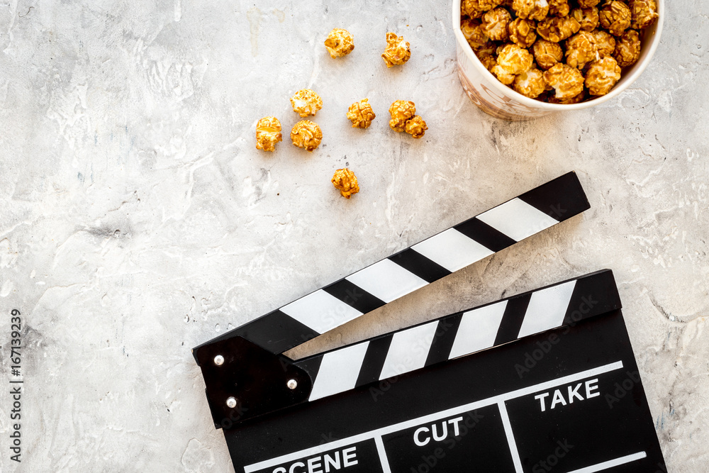 Popcorn for watching fim near clapperboard on grey background top view copyspace