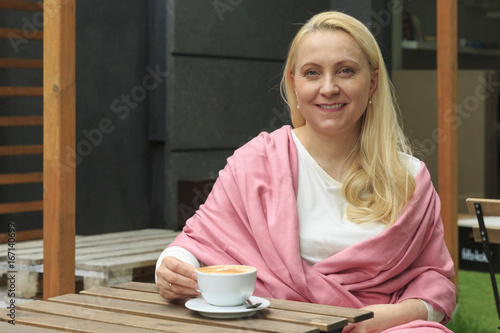 Smiling beautiful woman 45 years old drink coffee in a cafe.
