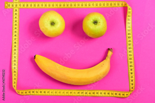 Apples and banana with yellow measuring tape make happy face photo