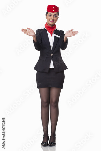 Portrait of young flight attendant gesturing over white background 