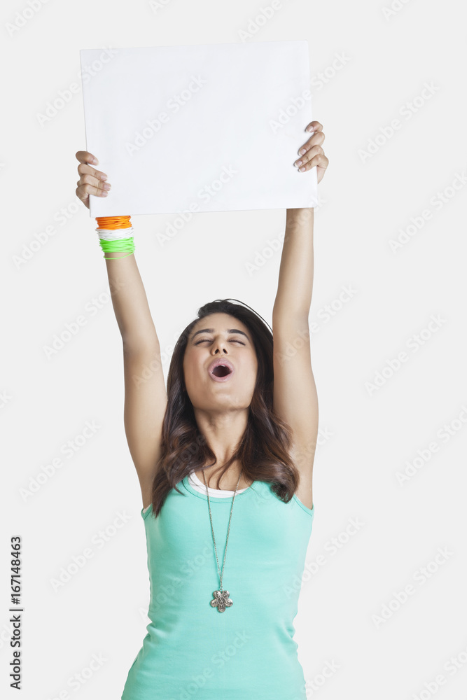 Young woman screaming while holding up a blank placard over white background Young woman screaming while holding up a blank placard over white background