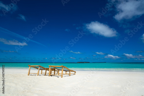 Empty wooden beach chairs on the tropical beach  vacation. Traveler dreams concept