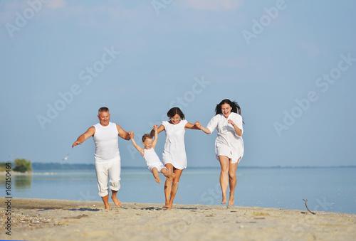 A cheerful family runs along the beach in the summer