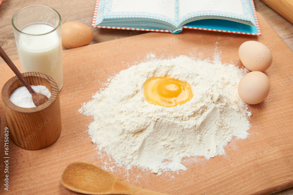 Flour and broken egg closeup for baking on a wooden background. Raw food and kitchen utensils. Flour and broken egg closeup for baking on a wooden background. Raw food and kitchen utensils.