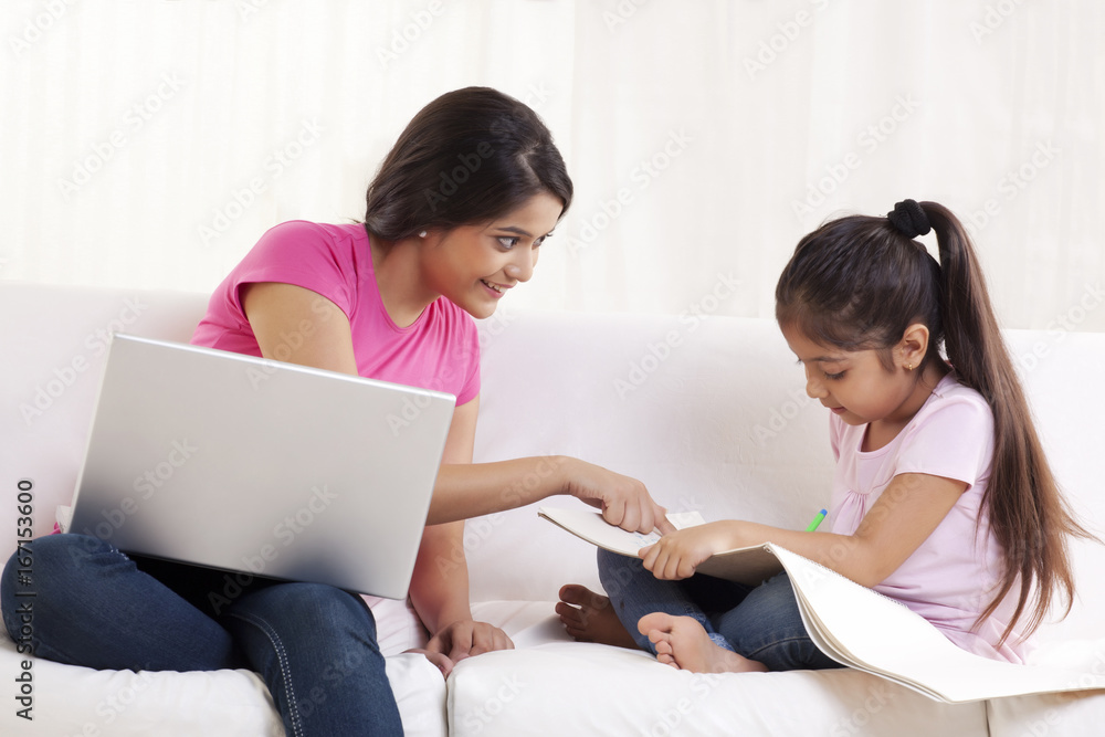 Happy young woman assisting her daughter in drawing Happy young woman assisting her daughter in drawing