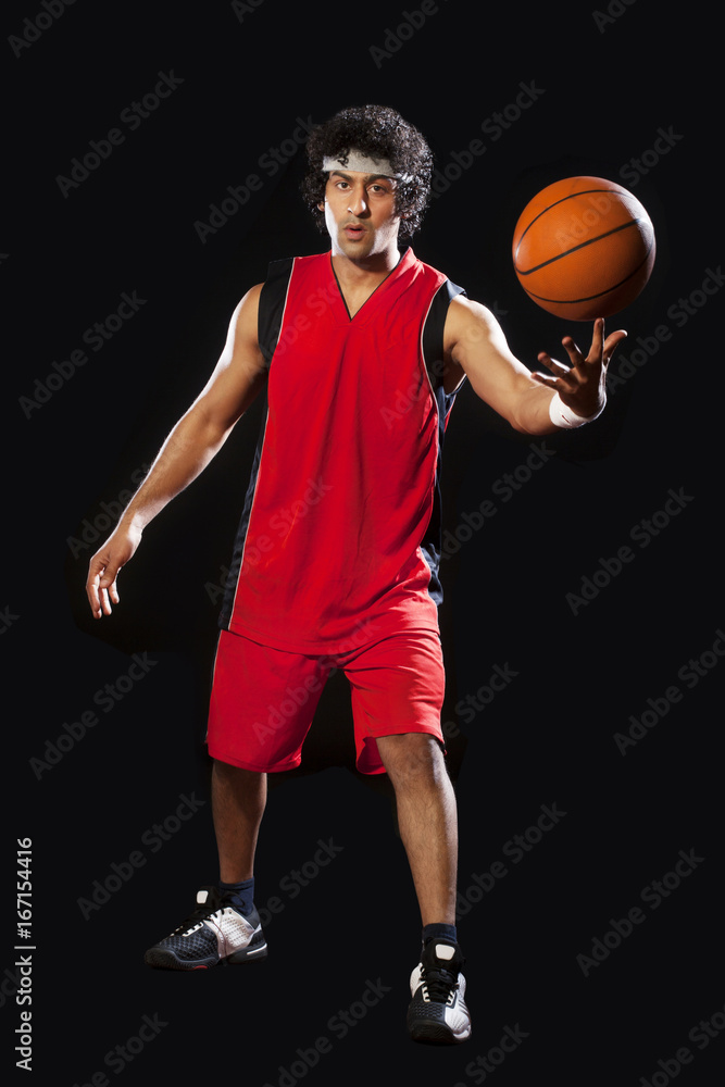 Naklejka premium Basketball player balancing ball on one finger 