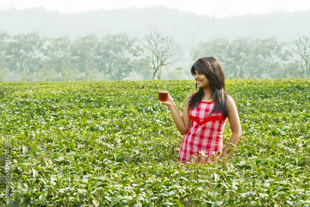 Woman standing in tea plantation with a cup of tea Woman standing in tea plantation with a cup of tea