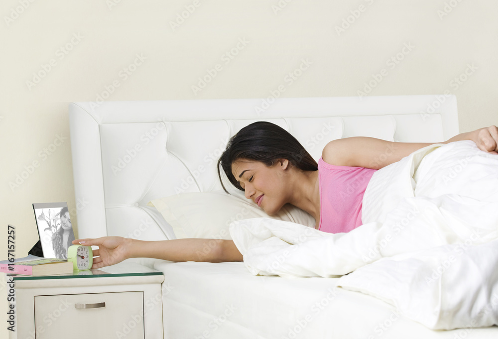 Girl switching off her alarm clock Girl switching off her alarm clock
