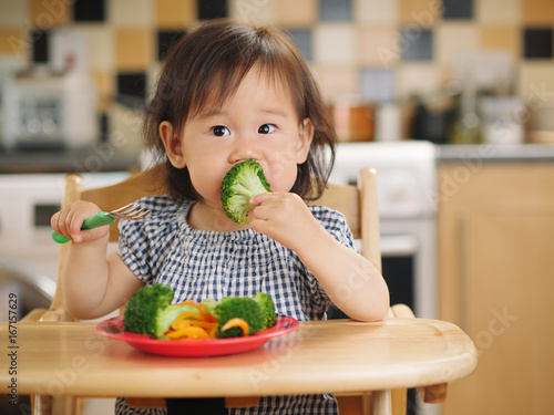 Canvas Print baby girl eating  vegetable at home