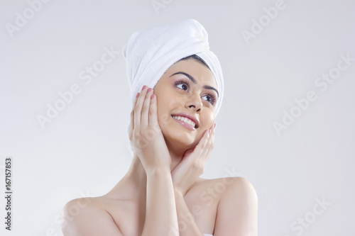 Beautiful woman with hair wrapped in towel looking away against white background