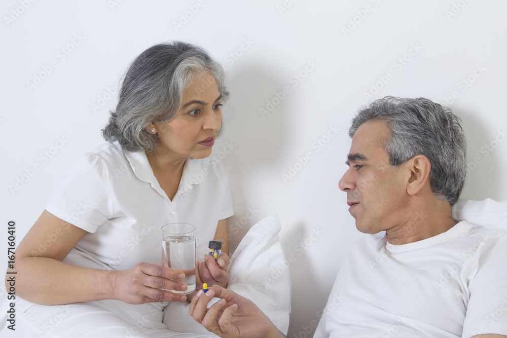 Wife giving medication to husband Wife giving medication to husband