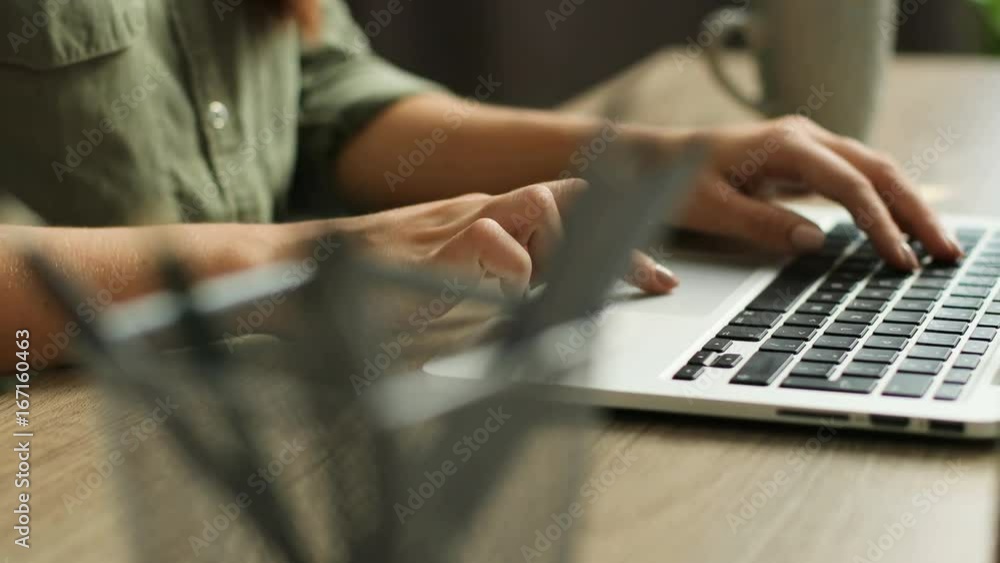 Close up video of female hands typing on laptop keyboard on a modern wooden table. Fingers tapping on keyboard Close up video of female hands typing on laptop keyboard on a modern wooden table. Fingers tapping on keyboard