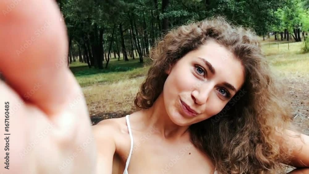 Young woman with curly hair posing for smartphone for selfie Young woman with curly hair posing for smartphone for selfie