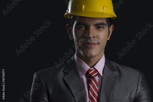 Portrait of confident male architect wearing hardhat against black background © IndiaPix