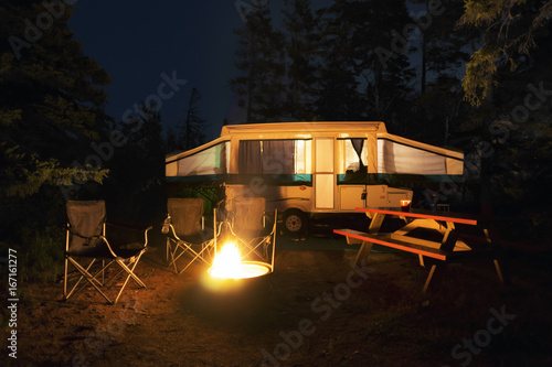 Wallpaper Mural Rv trailer, chairs and picnic table around a glowing campfire, wilderness site, night Torontodigital.ca