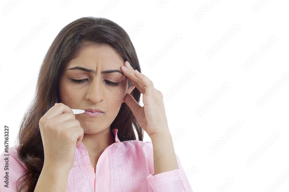 Woman measuring her fever through thermometer Woman measuring her fever through thermometer
