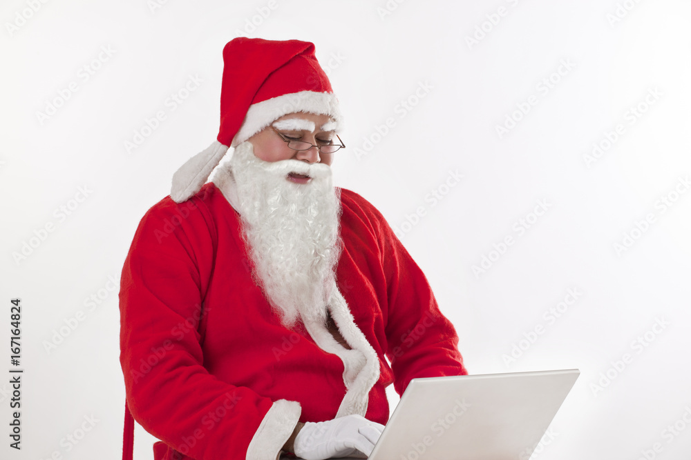 Naklejka premium Santa Claus operating laptop over white background 