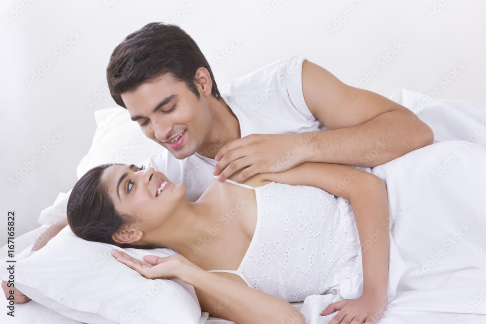 Romantic young couple looking at each other in bed Romantic young couple looking at each other in bed
