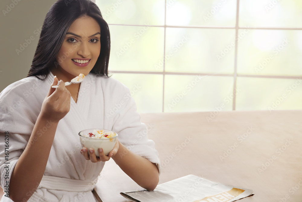 Portrait of young woman in bathrobe having breakfast at dining table Portrait of young woman in bathrobe having breakfast at dining table