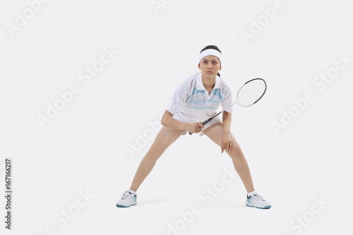 Woman in sports wear playing badminton against white background © IndiaPix