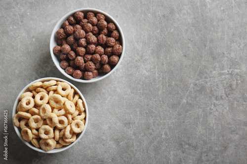 Bowls with different healthy breakfast cereals on gray background