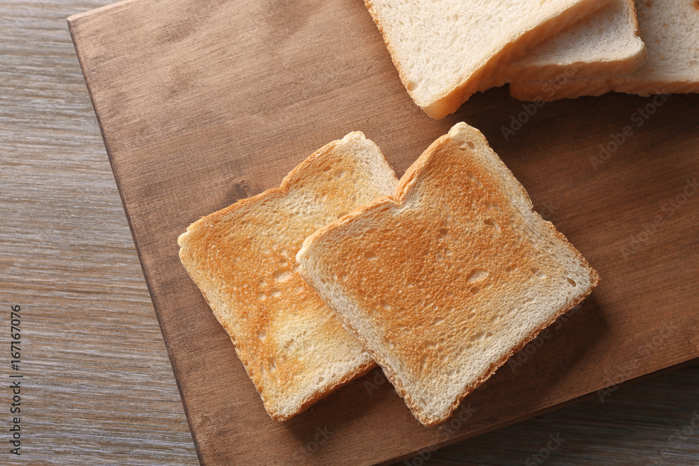 Wooden board with tasty breakfast toasts on table Wooden board with tasty breakfast toasts on table