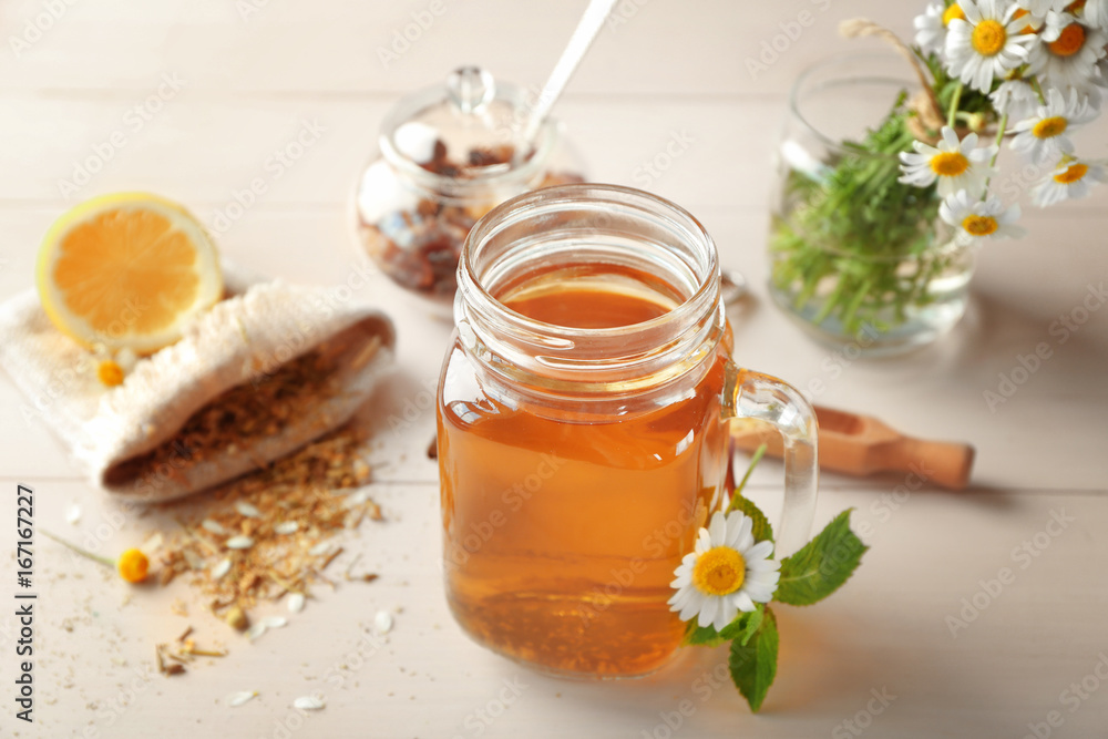 Mason jar with tasty chamomile tea on light wooden table Mason jar with tasty chamomile tea on light wooden table