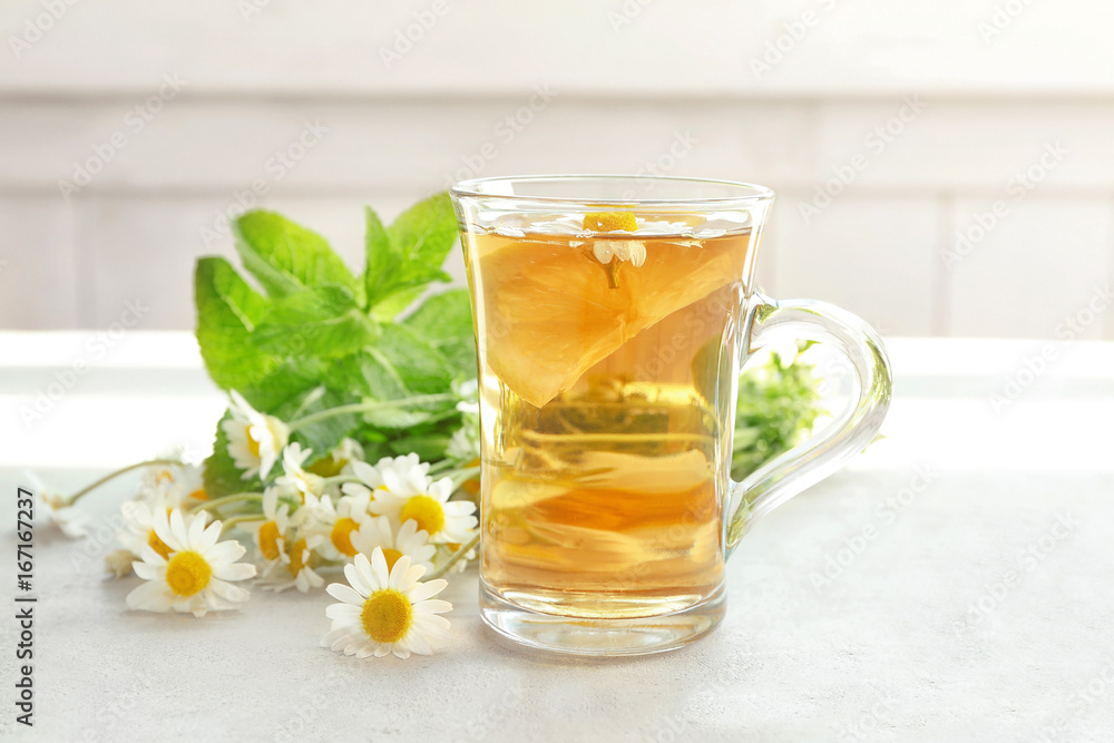 Herbal tea with lemon in glass cup and chamomile flowers on table Herbal tea with lemon in glass cup and chamomile flowers on table