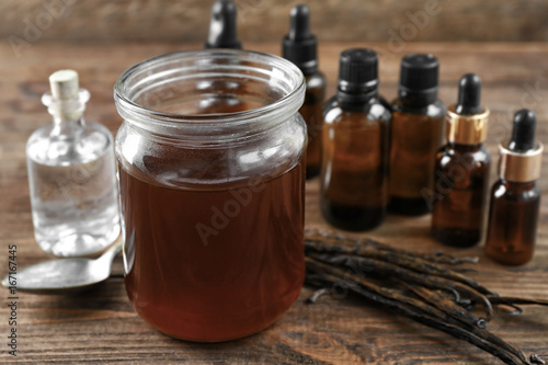 Jar with aromatic vanilla extract on table
