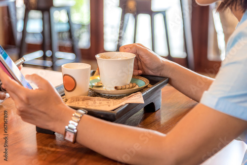 Woman drink coffee and use mobile phone in coffee shop.