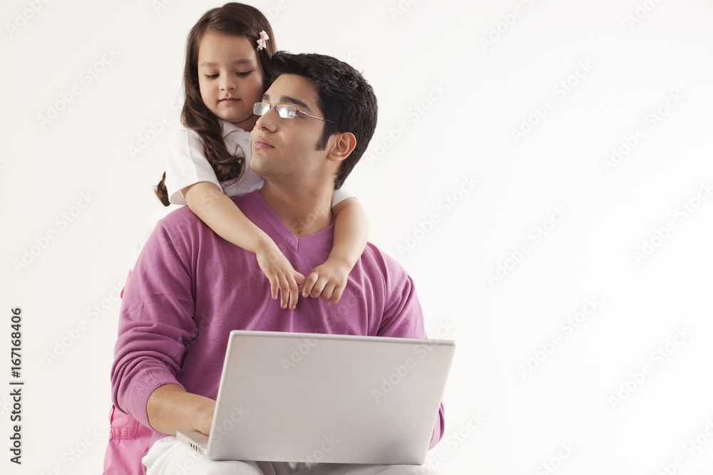 Man looking at daughter while using laptop 