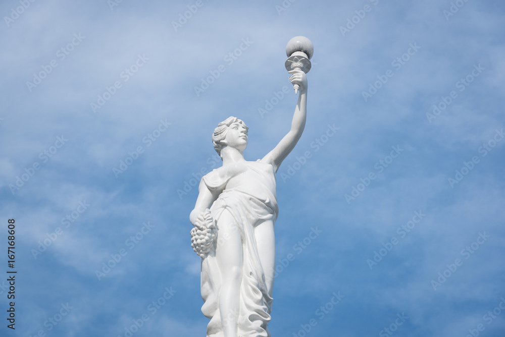 Statue of an ancient Greek man carrying a torch against with blu