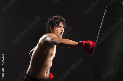 Young man hitting punching bag 